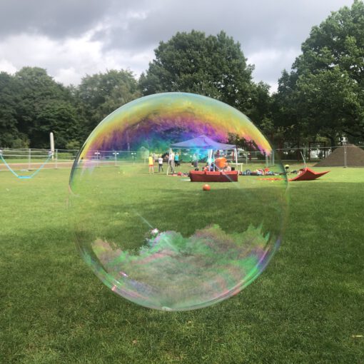 Eine große Seifenblase fliegt durch einen Park