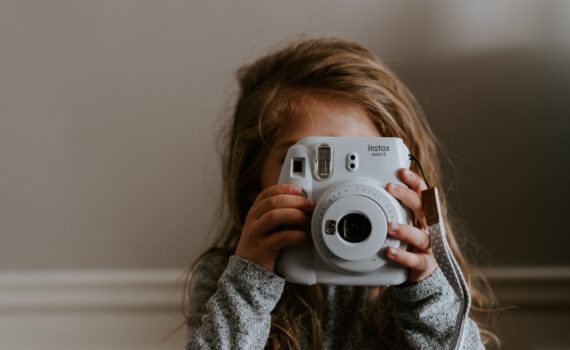 Ein Kind mit einer Polaroidkamera in der Hand
